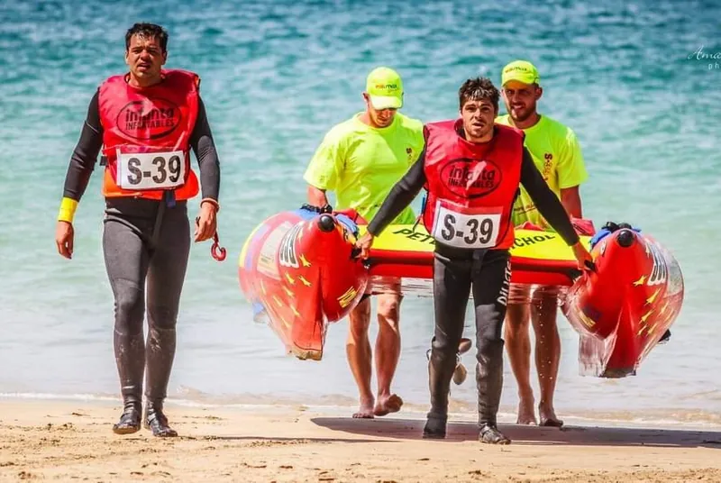 Peter Groenenstein and his crew carrying a red inflatable racing boat off the beach